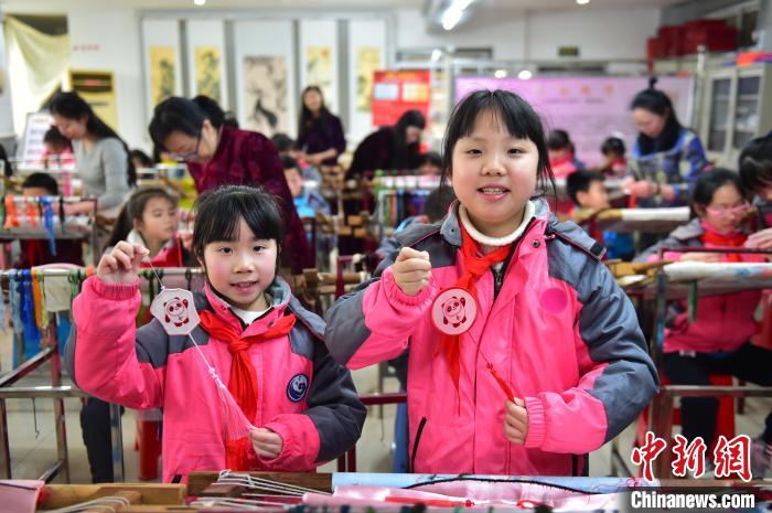 圖為小學生展示繡制好的2022年北京冬奧會吉祥物“冰墩墩”形象?！∮髟屏?攝