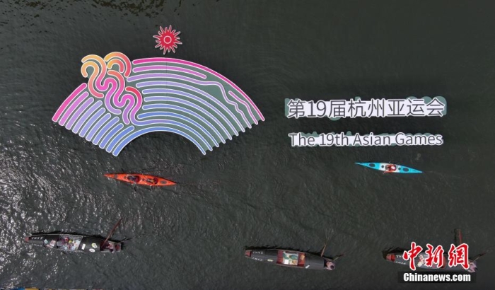 資料圖為烏篷船和皮劃艇從杭州亞運會標識前劃過。王剛 攝