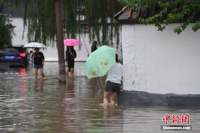 7月31日，市民行走在雨中的北京房山區瓦窯頭村。北京市氣象臺當日10時發布分區域暴雨紅色預警信號。北京市水文總站發布洪水紅色預警，預計當日12時至14時，房山區大石河流域將出現紅色預警標準洪水。<a target='_blank' href='/'><p  align=