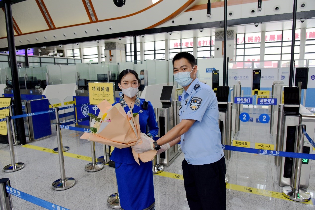 磨憨出入境邊防檢查站民警為中老鐵路第100萬名出入境旅客，D888次國際旅客列車老撾籍乘務員森達拉·妮緹婭（Sengdala Nitiya），送上鮮花。黃遠飛 攝