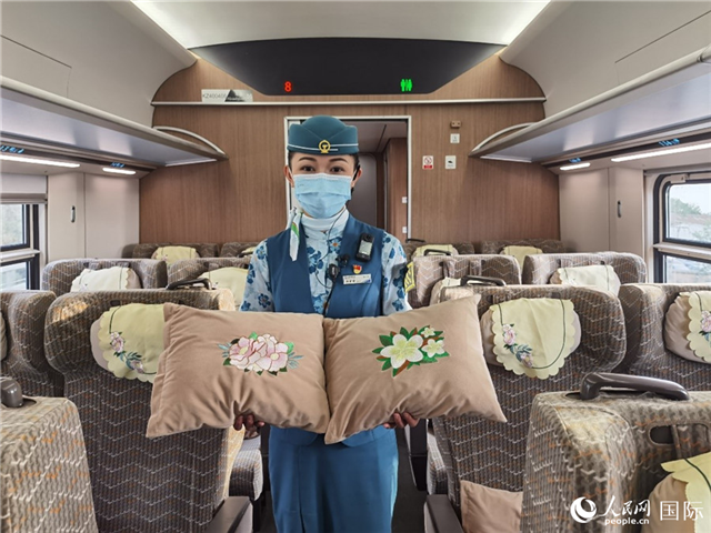 趙瑩靜展示中老鐵路國際旅客列車里帶有中國牡丹花和老撾占巴花刺繡圖案的靠墊。人民網記者 杜明明攝