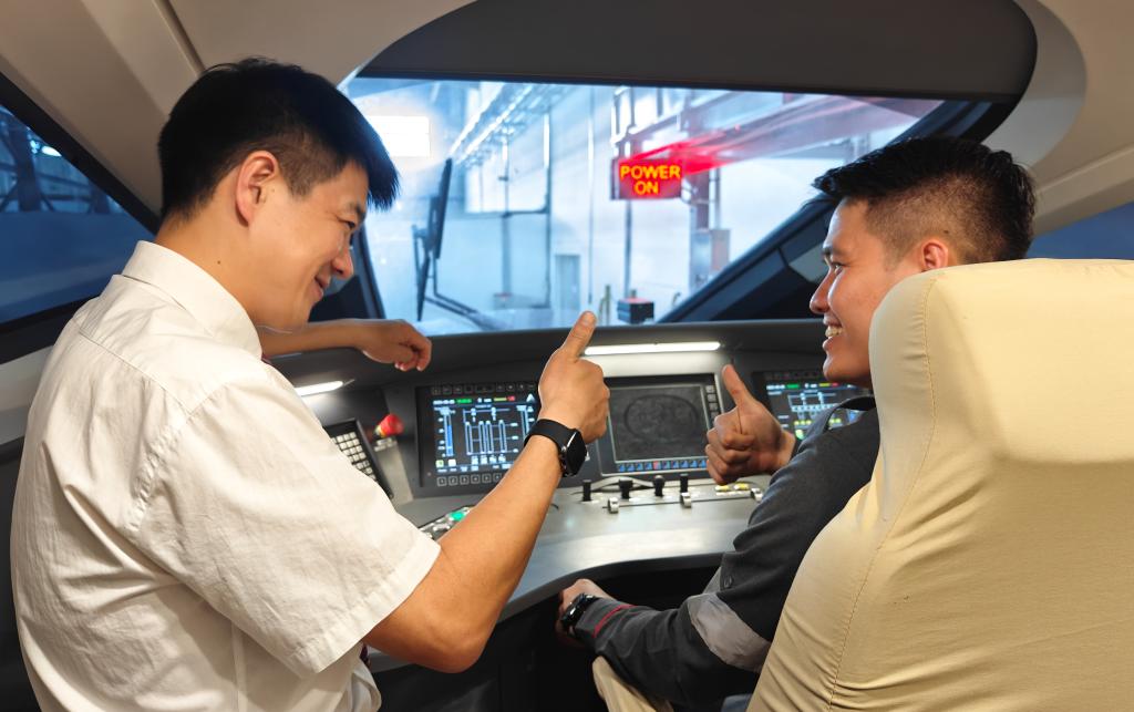 8月25日，在印度尼西亞萬隆的雅萬高鐵德卡魯爾動車所內，中國師傅穆振（左）在向印尼火車司機塞蒂亞萬講解動車組出庫前的上電作業。