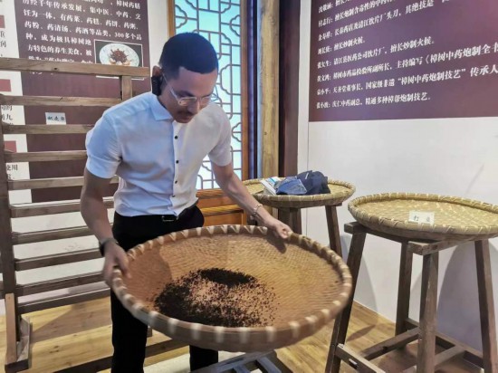 2023“一帶一路”媒體合作論壇聯合采訪團團員在非遺文化展示館體驗中藥炮制技藝。（本報記者 黃超攝）