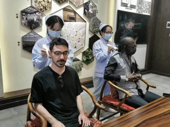 2023“一帶一路”媒體合作論壇聯合采訪團團員在九牛草展示館體驗艾灸。（本報記者 黃超攝）