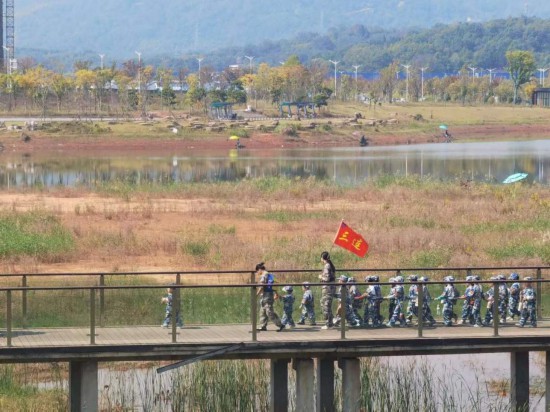 　　10月24日，秋游的幼兒園小朋友在老師帶領下走在清水塘公園里的木橋上。本報記者 常雯宜攝