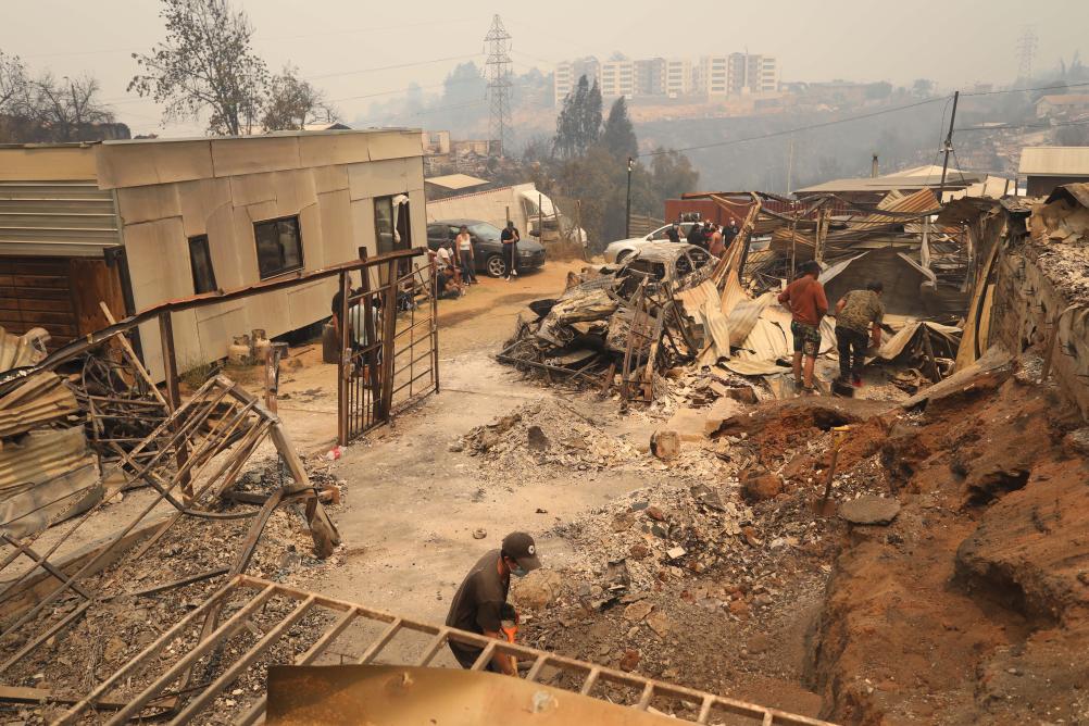 2月3日，在智利瓦爾帕萊索大區比尼亞德爾馬市，當地民眾清理在森林火災中燒毀的房屋。新華社發