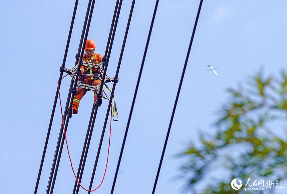 3月11日，在浙江省諸暨市河上鎮，浙江省送變電工程有限公司檢修人員在高空的導線上進行線路檢修維護。人民網 章勇濤攝
