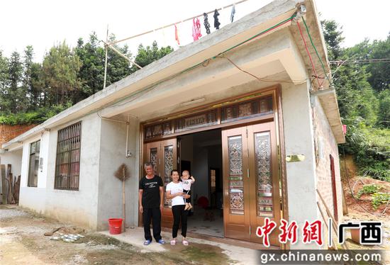 7月4日，在廣西柳州市融安縣大坡鄉崗偉村，脫貧戶肖裕安（左）與妻子、外孫在改造后的房屋前合影。覃慶和 攝