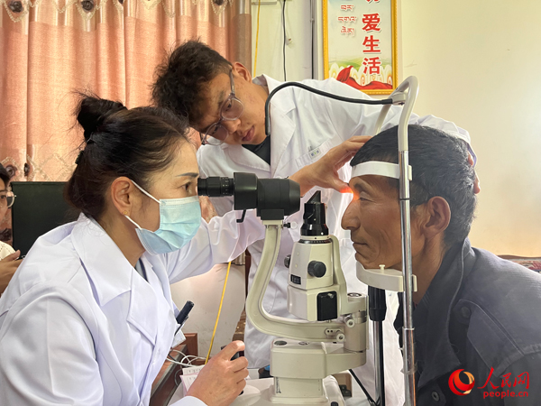 王紅英（左）和團隊成員為達熱村村民檢查眼睛。人民網記者 杜燕飛攝