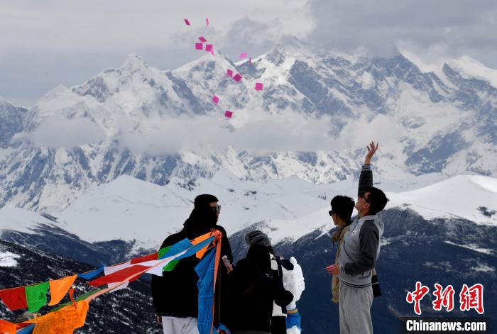 圖為5月14日，游客在西藏林芝色季拉山觀景臺拋灑“隆達”(風馬旗，藏族民眾的一種祈福方式)?！±盍?攝