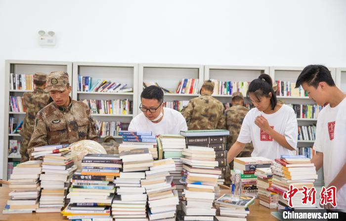 圖為志愿者們和邊防戰士整理圖書?！詵| 攝