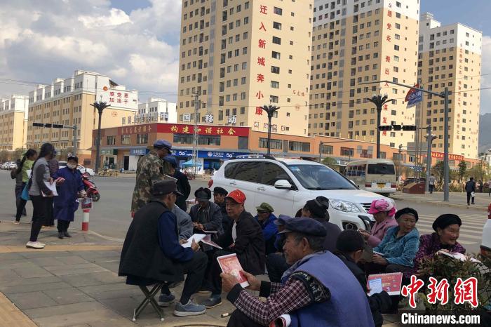 圖為會澤縣城易地扶貧搬遷安置點內，老人們聚在廣場上聊天，身后是他們的新家?！】姵?攝