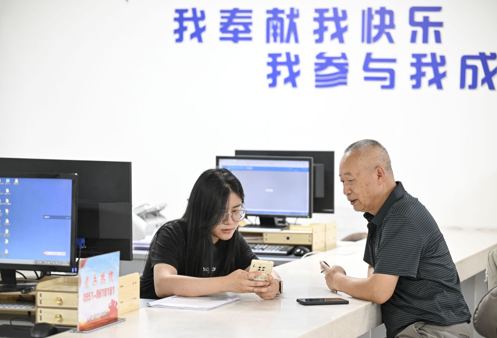 2024年6月20日，在寧夏銀川市金鳳區長城花園社區黨群服務中心，工作人員幫助居民辦理業務。圖片來源 新華社