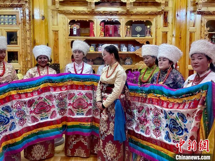 圖為女性展示村民自發繡制的“百米五彩哈達”?！±钣穹?攝