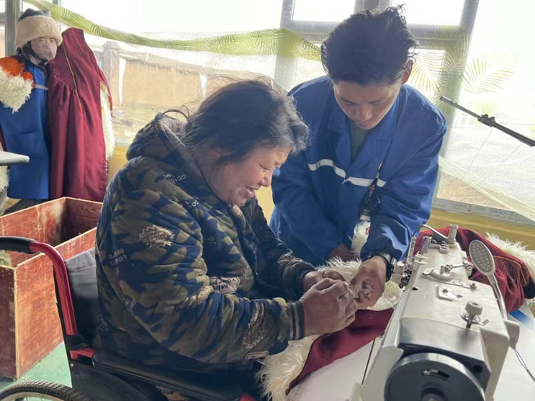 扎西奪爾登幫助殘疾員工裁剪。阿壩州文明辦供圖