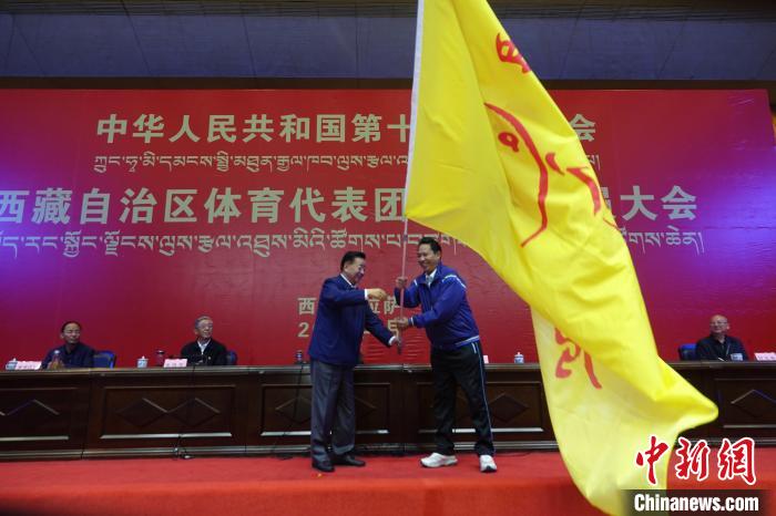 西藏自治區副主席甲熱·洛桑丹增授代表團團旗，西藏自治區體育局局長尼瑪次仁接旗?！∪轿木?攝