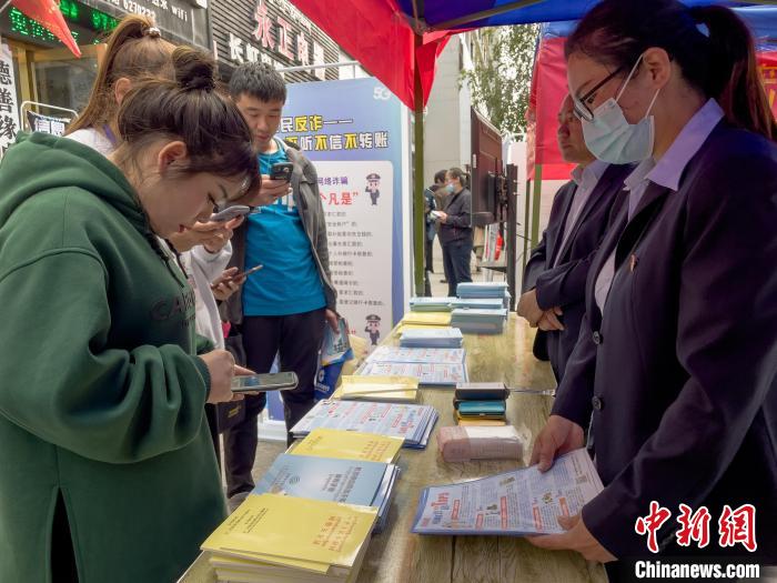 圖為工作人員正在向路過市民介紹國家反詐中心軟件的功能?！≈x牧 攝