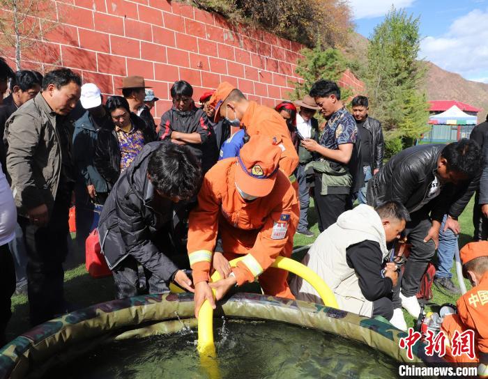 圖為森林消防員為護林員講解滅火裝備的使用方法?！〔际猩窒乐ш?供圖