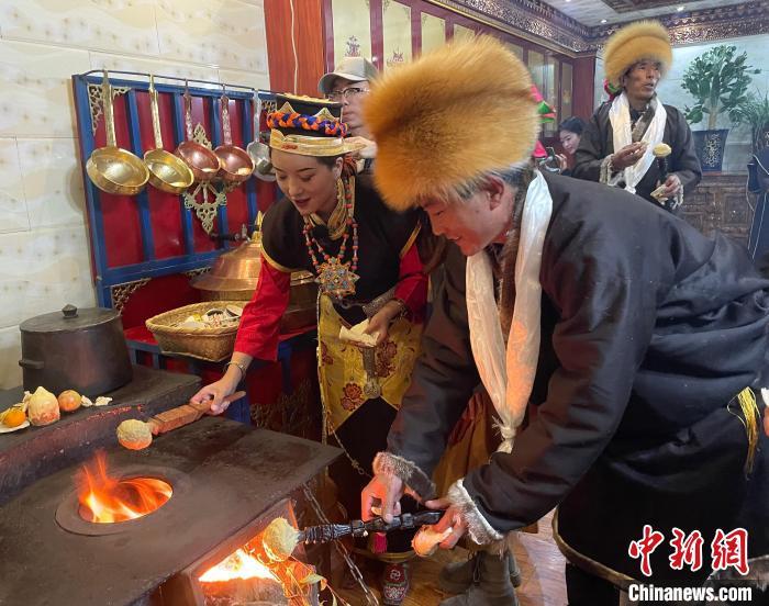 圖為人們在火上烤節日美食“結達”?！∪轿木?攝