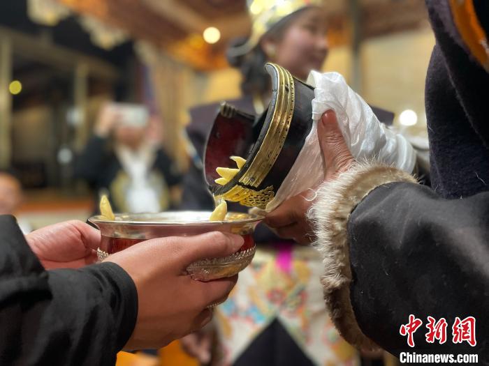 圖為主人在碗中斟滿青稞酒?！∪轿木?攝