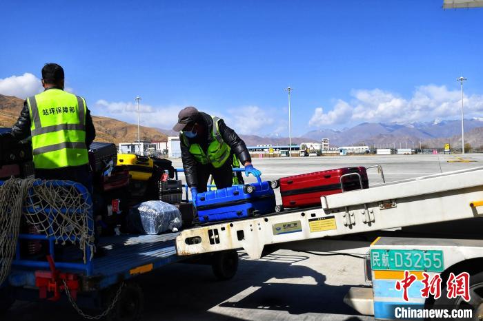 圖為機場工作人員傳送旅客行李箱?！≈芎?攝