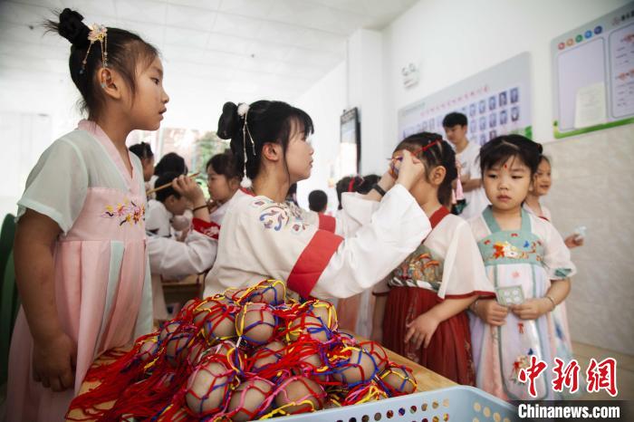 圖為幼兒園的老師們穿上漢服為小朋友們戴上彩蛋，寓意著幸福安康?！《^生 攝