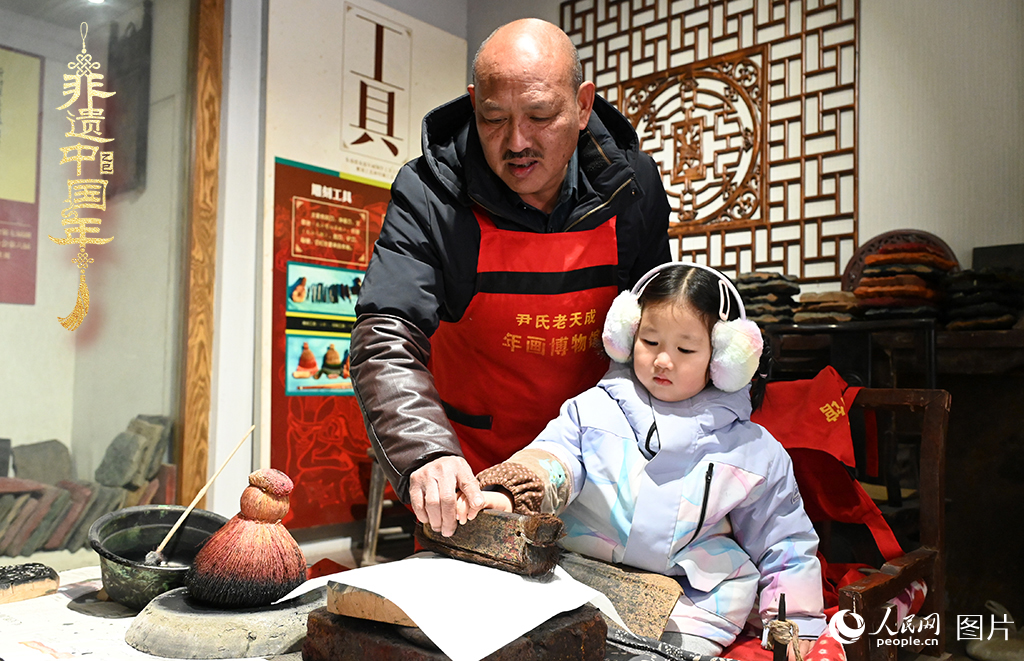 2025年1月27日，河南開封朱仙鎮木版年畫藝人尹國法指導小朋友研習年畫印制技藝。朱仙鎮木版年畫源自漢唐壁畫藝術，是中國木版年畫的鼻祖。2006年5月20日，朱仙鎮木版年畫經國務院批準列入第一批國家級非物質文化遺產名錄。人民網記者 王玉興攝